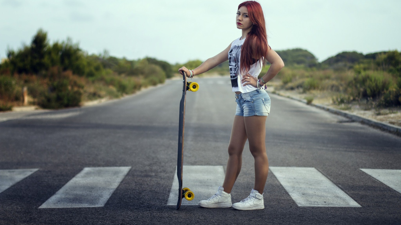 Девушка со скейтбордом стоит на переходе