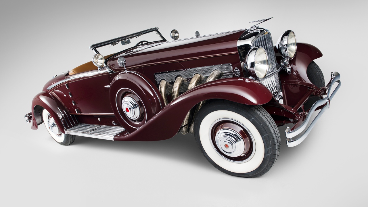 Бордовый ретро автомобиль Duesenberg Model J 530 на сером фоне