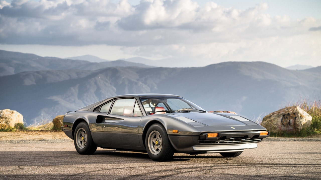 Суперкар Ferrari 308 gts серого цвета,   на фоне гор 