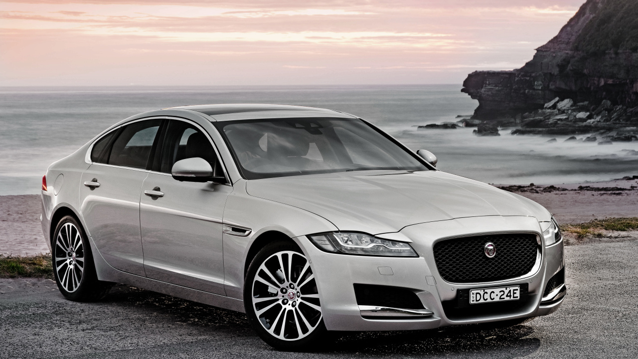 Серебристый автомобиль Jaguar XF на фоне океана