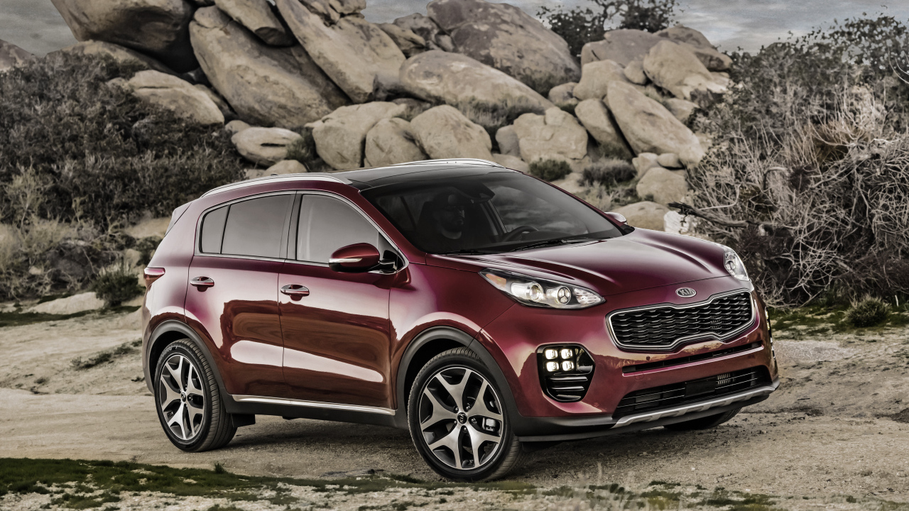 Стильный бордовый внедорожник Kia Sportage на фоне больших камней