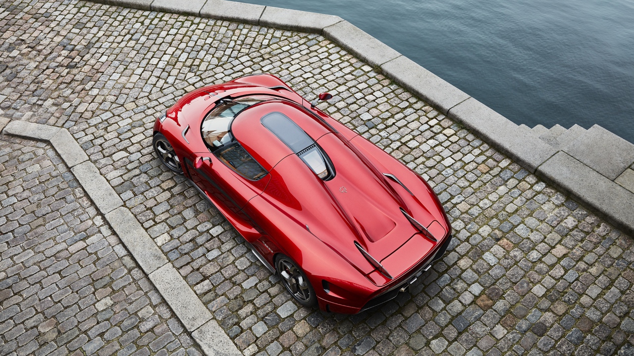 Красный спортивный автомобиль Koenigsegg Regera у воды, вид сверху