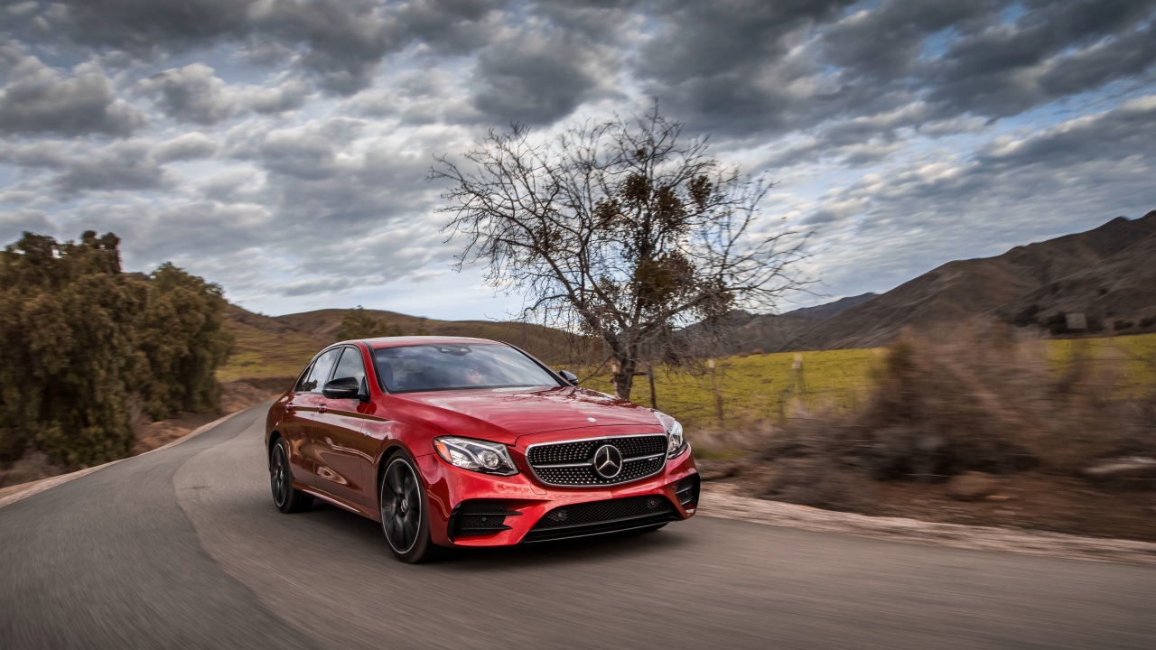 Стильный красный автомобиль Mercedes-Benz E-Class на фоне неба 