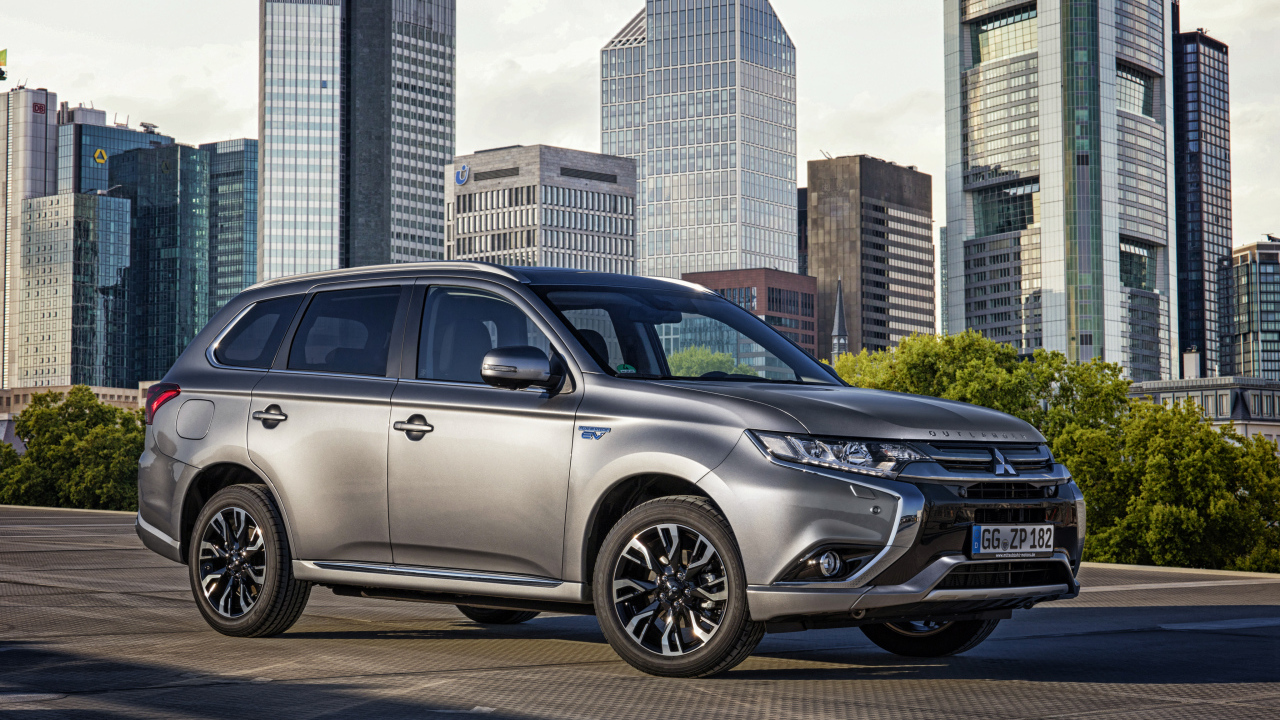 Серебристый автомобиль Mitsubishi Outlander на фоне небоскребов 