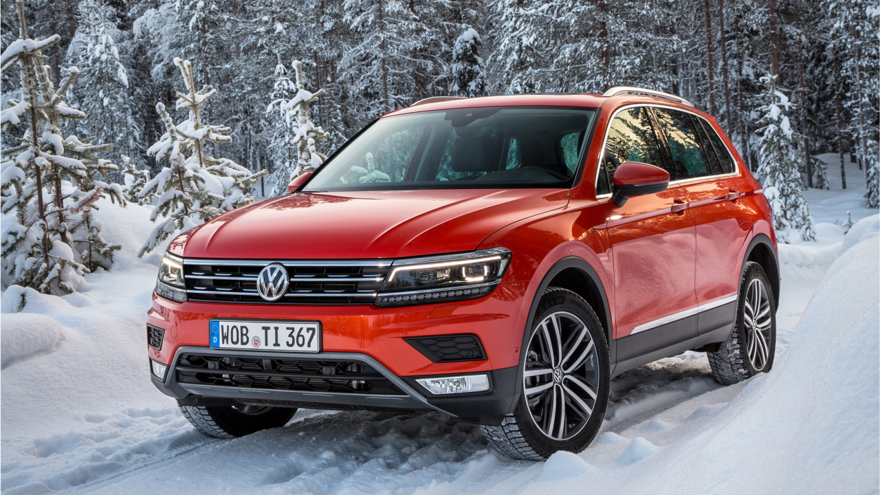 Красный Volkswagen Tiguan 2017 года в заснеженном лесу 