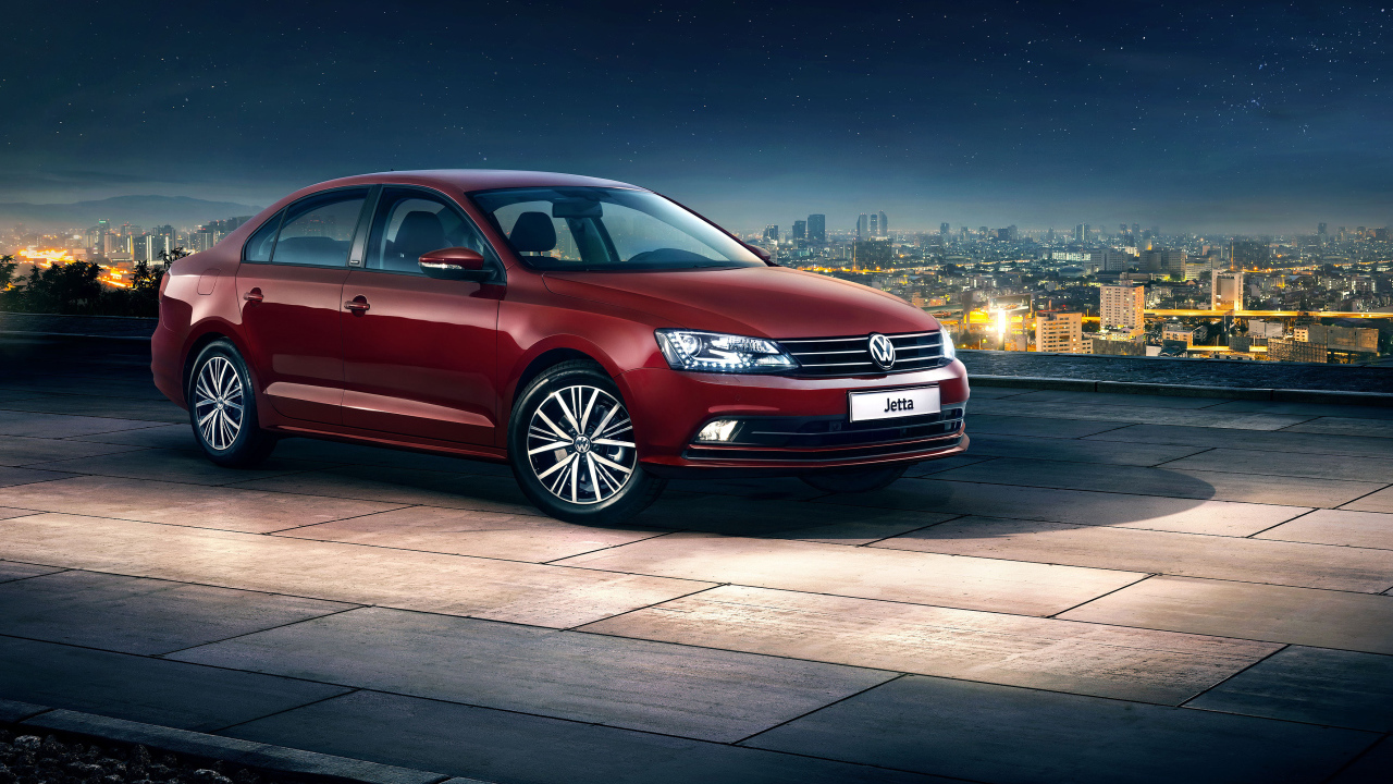 Красный автомобиль Volkswagen Jetta на фоне ночного города