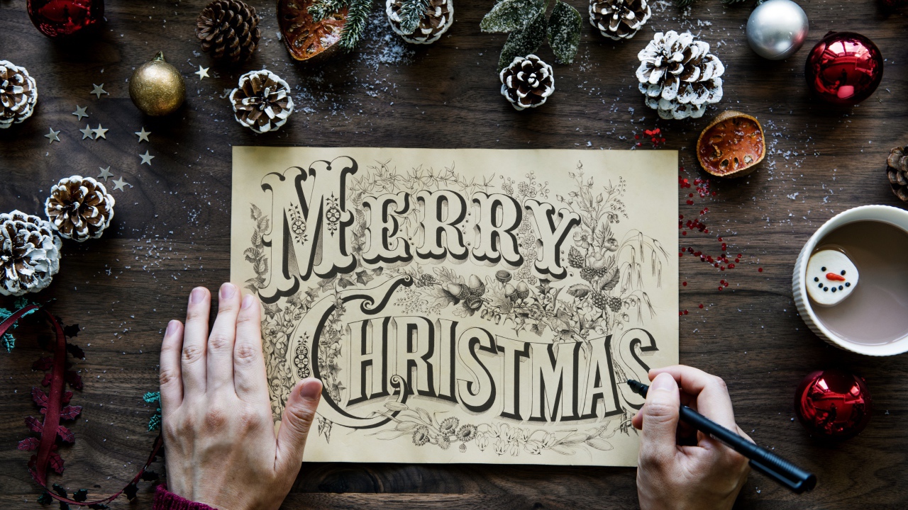 A drawing with the inscription Merry Christmas on the table with Christmas decorations