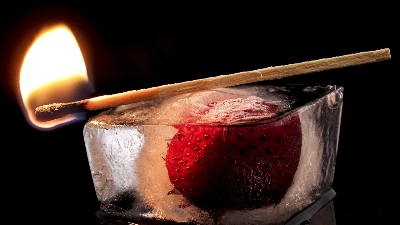 Зажженная спичка на кусочке льда с клубникой 