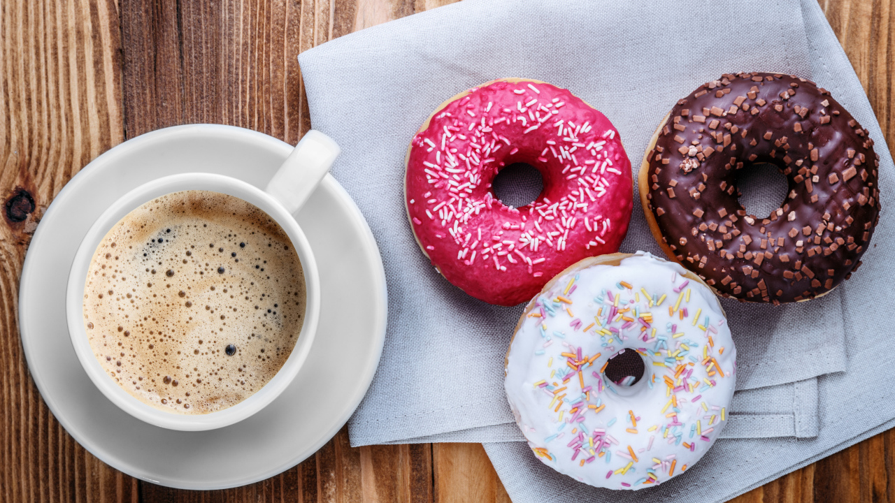 Чашка кофе с тремя аппетитными пончиками на столе