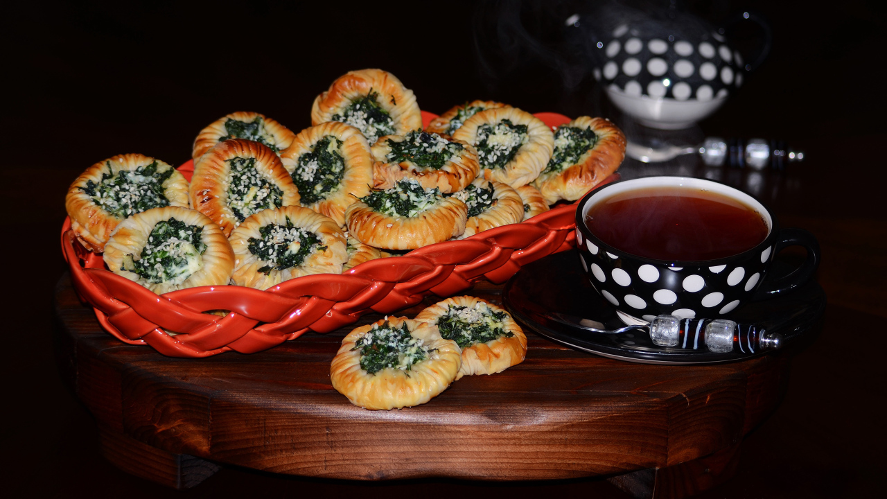 Булочки с зеленью и горячим чаем на черном фоне