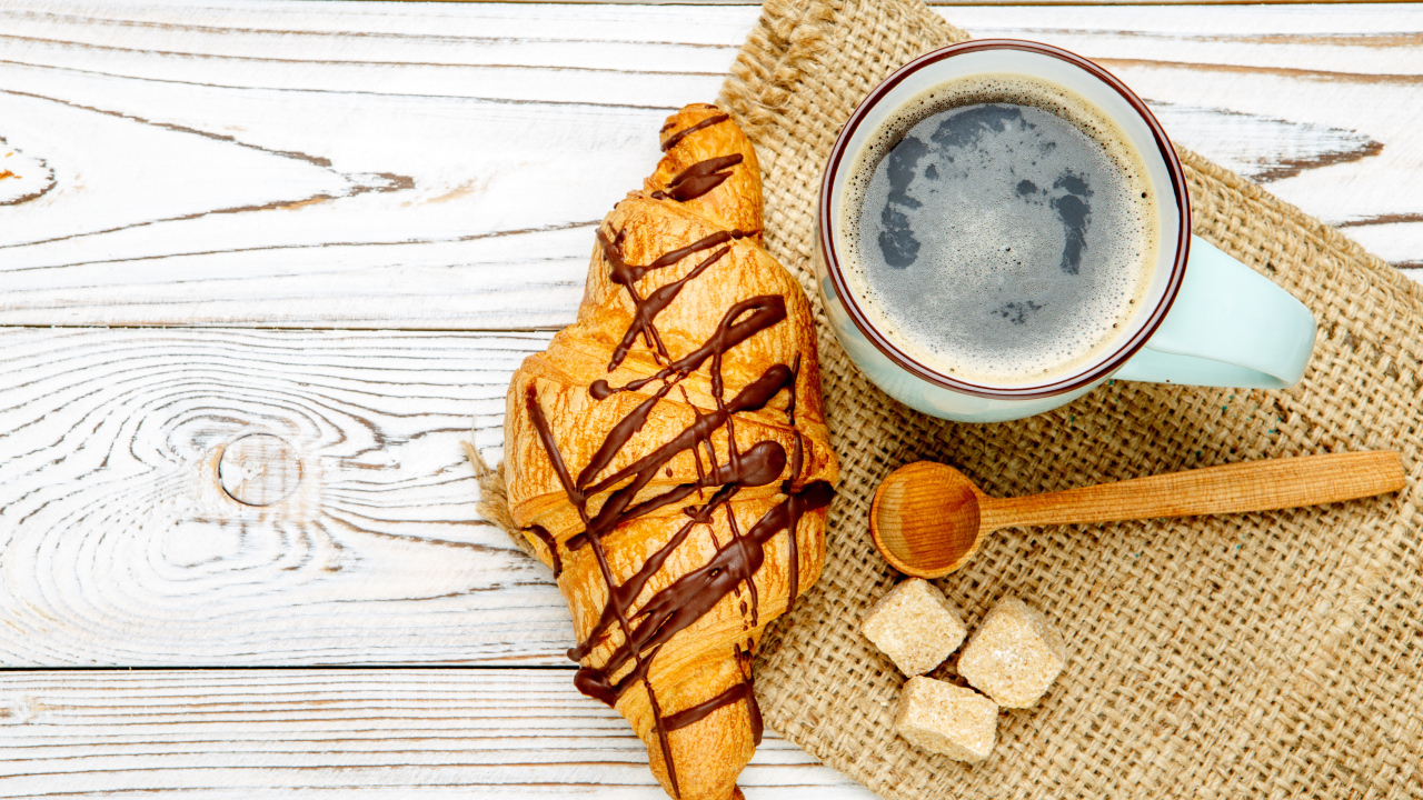 Круассан с шоколадом и чашкой кофе на столе