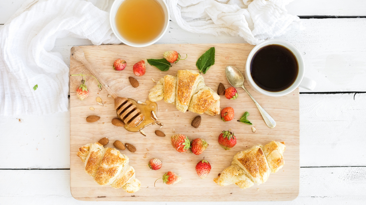 Круассаны, мед, свежие ягоды клубники и кофе на завтрак