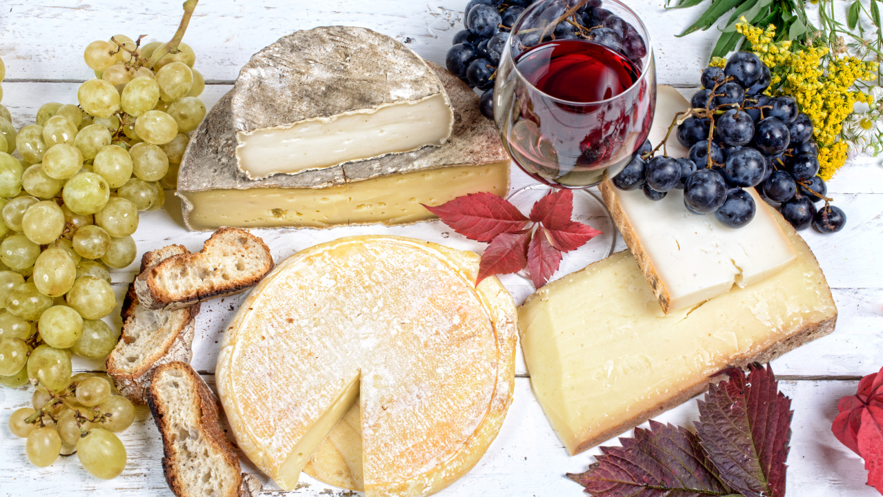 Дорогой сыр с плесенью на столе с виноградом и красным вином