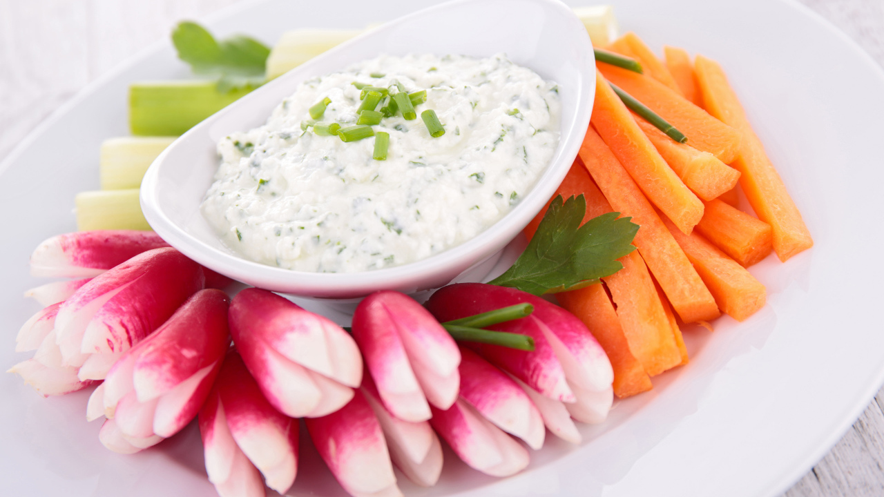 Свежие овощи с соусом в белой тарелке 