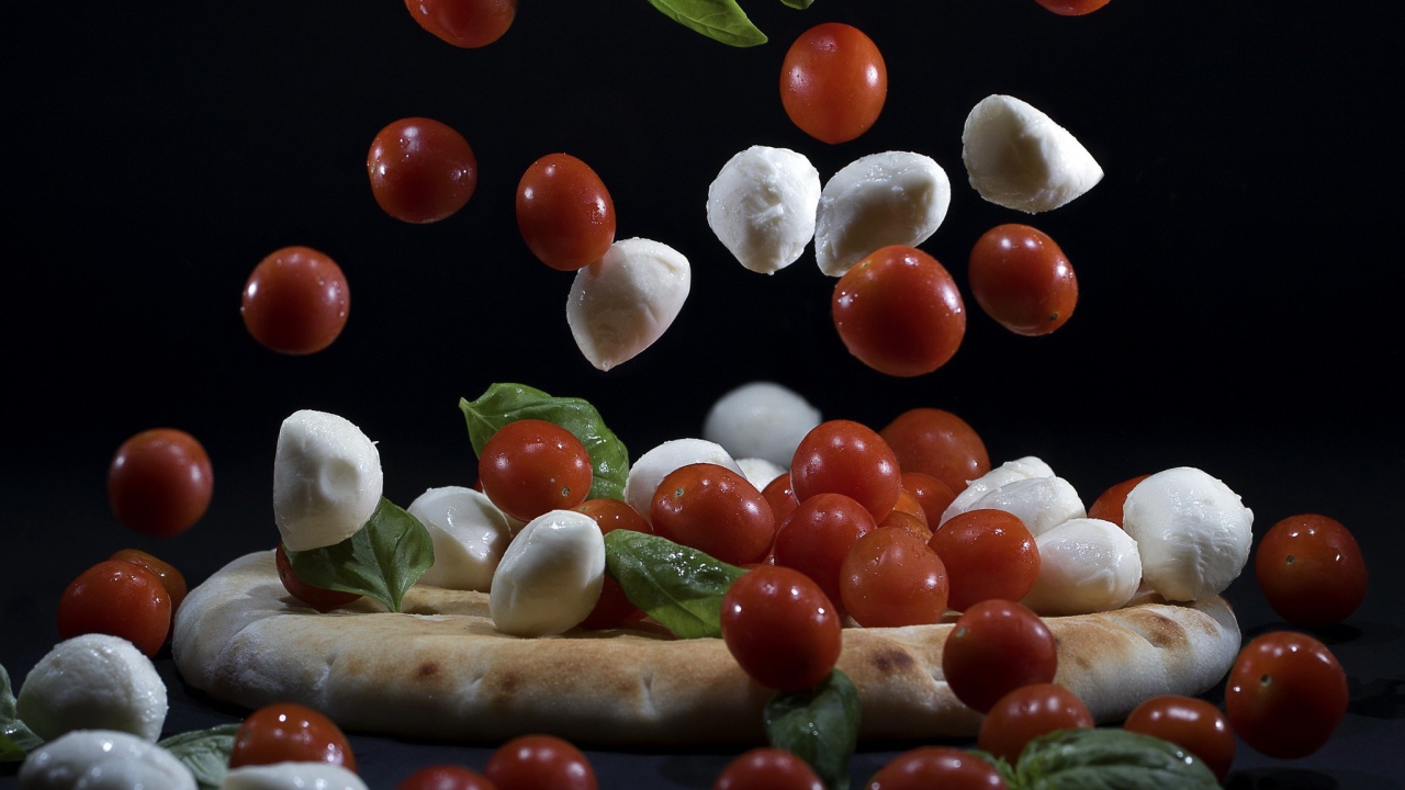 Помидоры и сыр Моцарелла падают на пиццу 