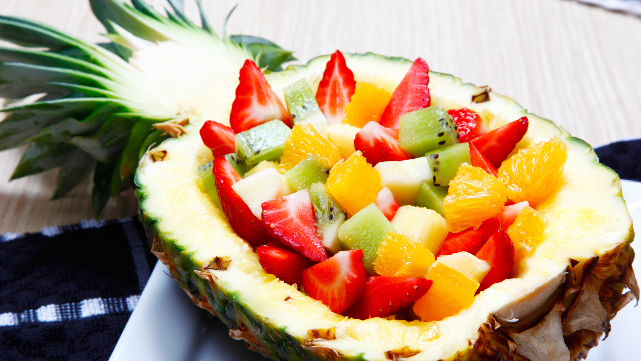 Фруктовый салат из цитрусовых  в тарелке из свежего ананаса 