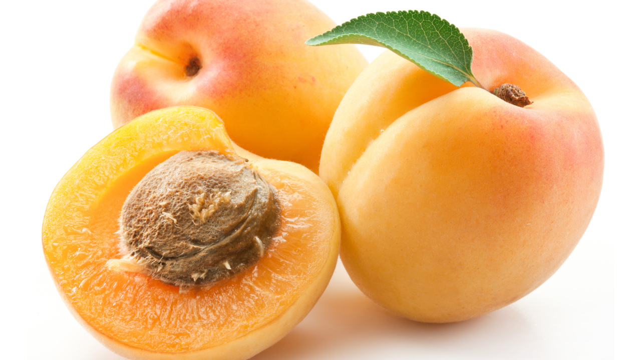 Три спелые крупные абрикосы на белом фоне