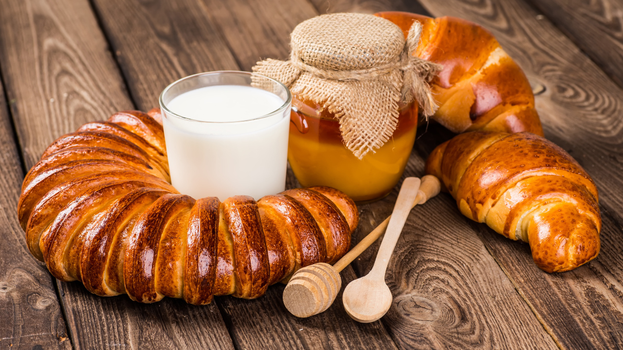 Свежая выпечка на столе со стаканом молока и медом