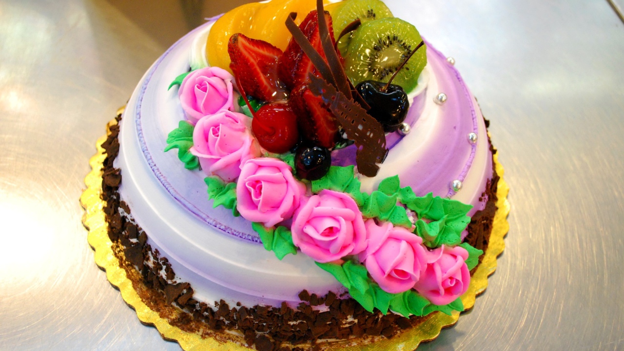 Красивый торт с фруктами украшен розовыми розами из крема