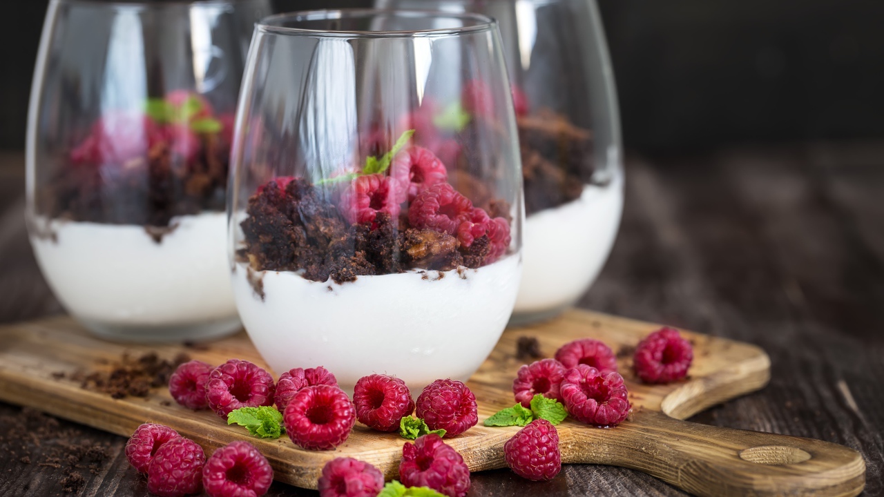 Десерт со сливками, шоколадом и свежей малиной в стеклянных стаканах