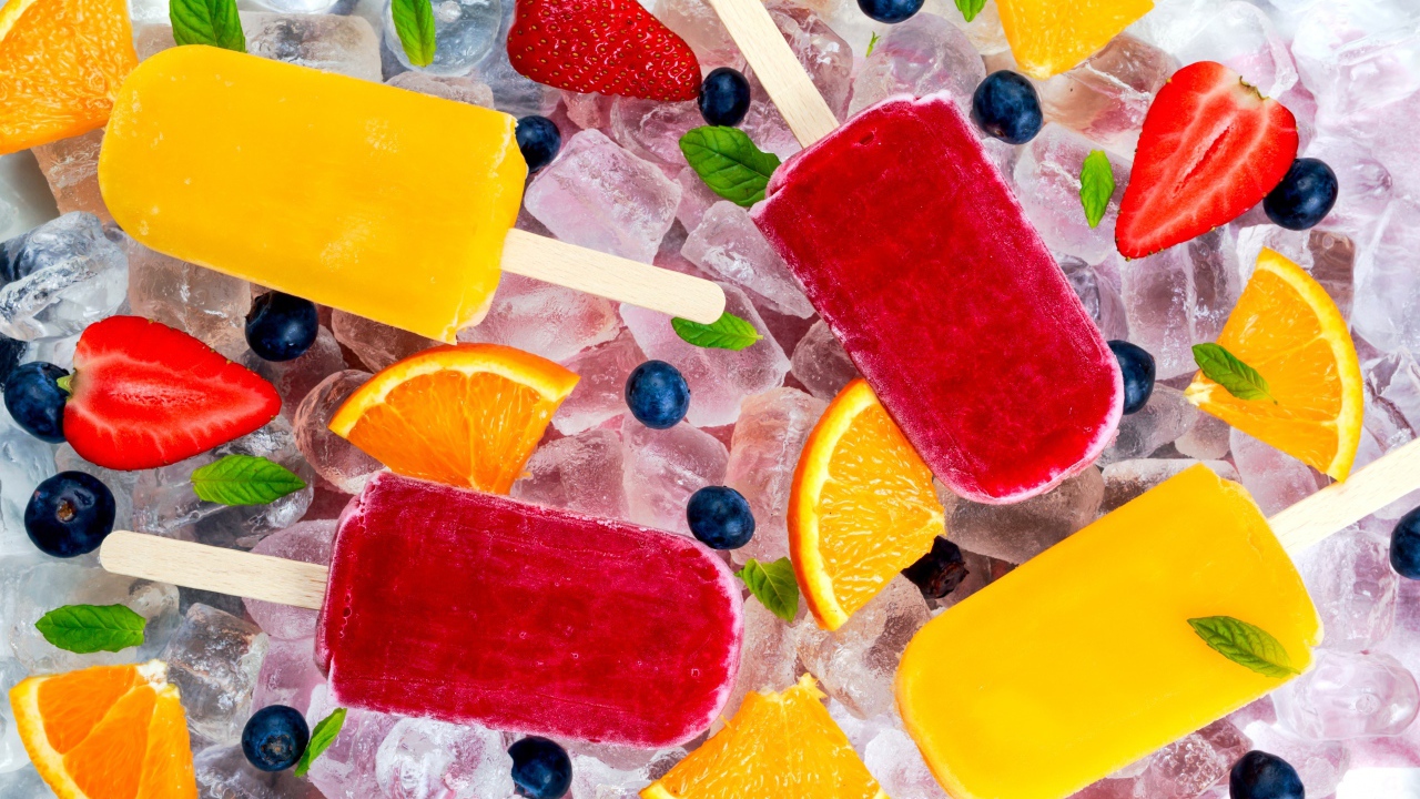 Разноцветное фруктовое мороженое с ягодами лежит на кусочках льда