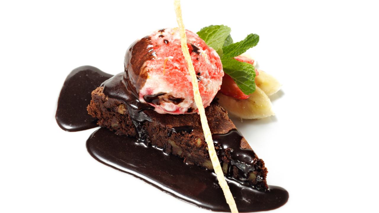 Кусок пирожного с шоколадом и шариком мороженого на белом фоне