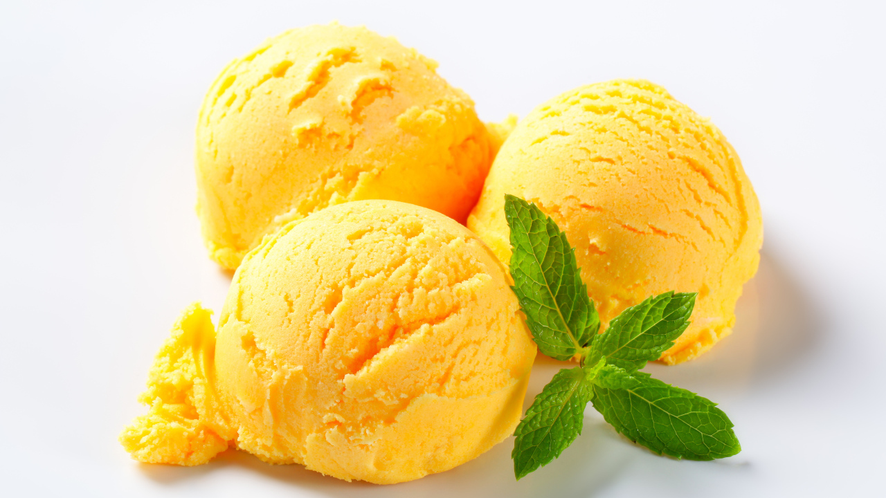 Три шарика фруктового мороженого с листиком мяты на белом фоне