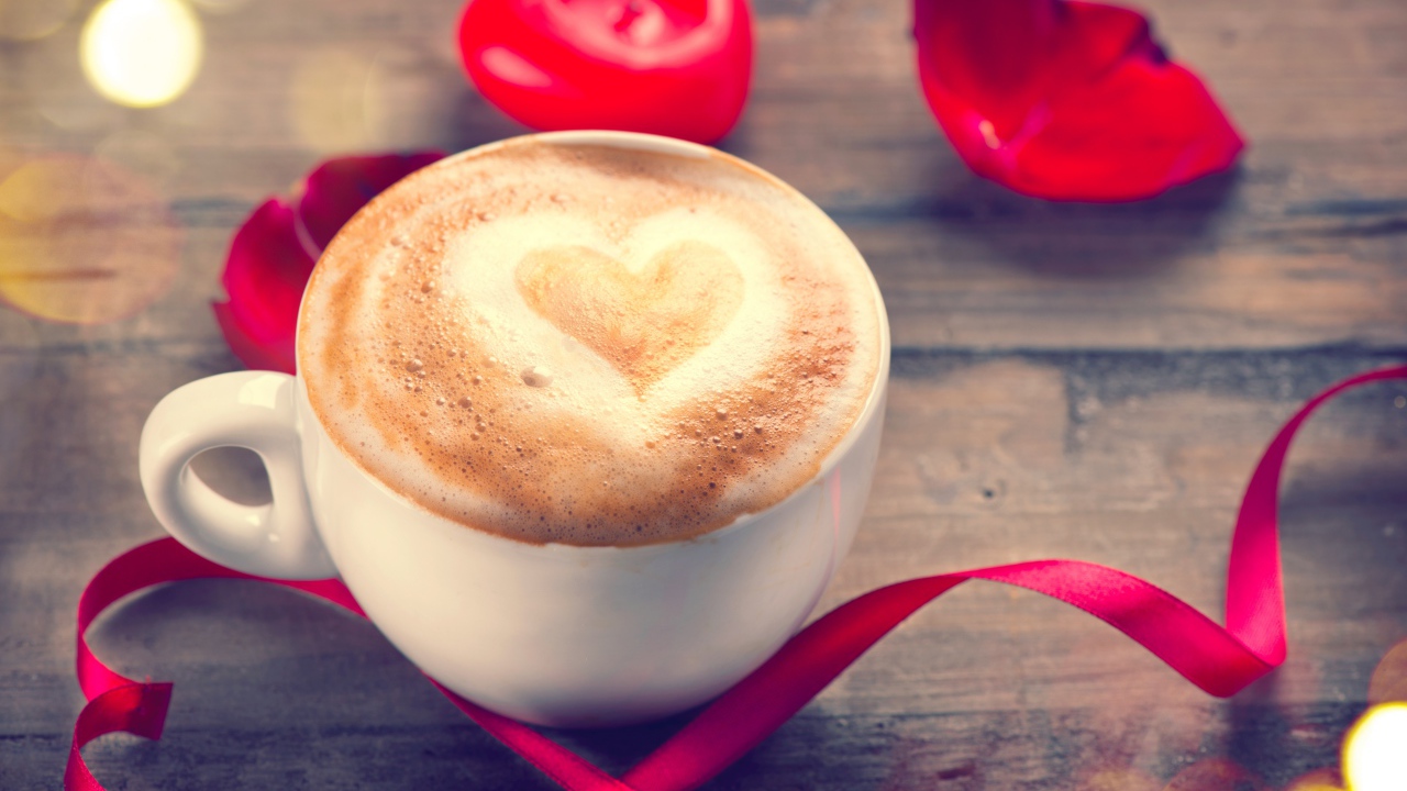 Чашка кофе на столе с красной свечой и лентой