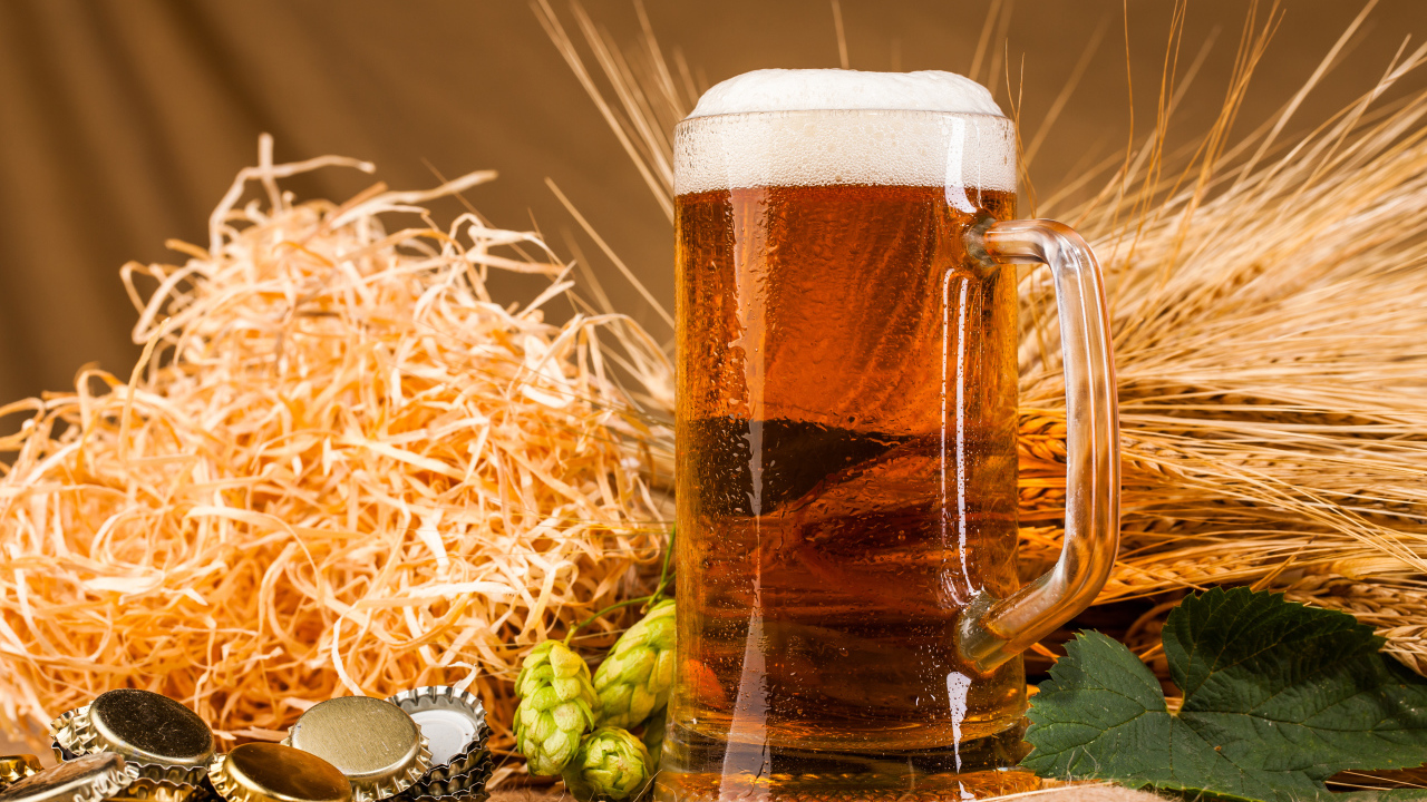 Бокал пива с пеной на столе с хмелем и соломой