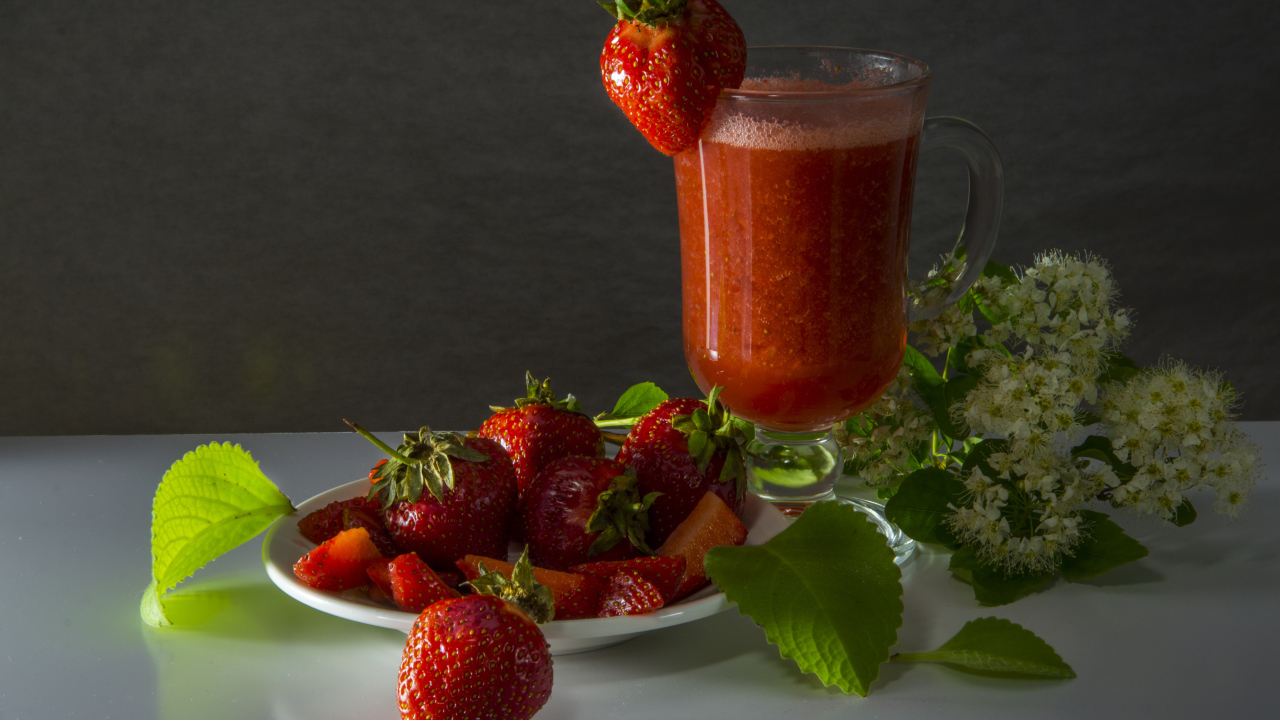 Стакан клубничного сока и свежая клубника на столе