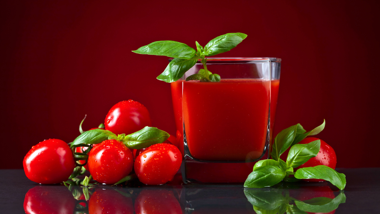 Стакан томатного сока со свежими помидорами на столе