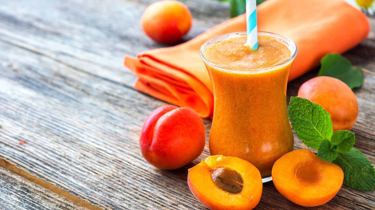Абрикосовый смузи в стакане на столе со свежими ягодами