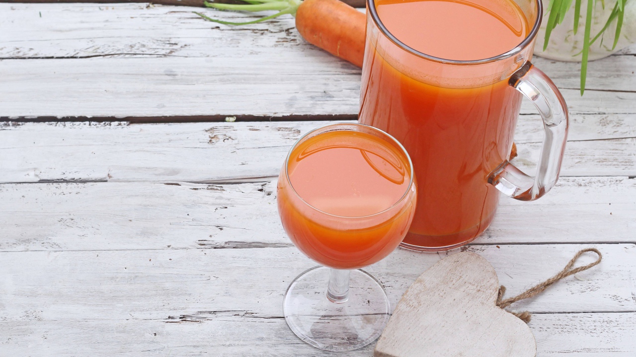 Морковный сок в кувшине на столе с  бокалом