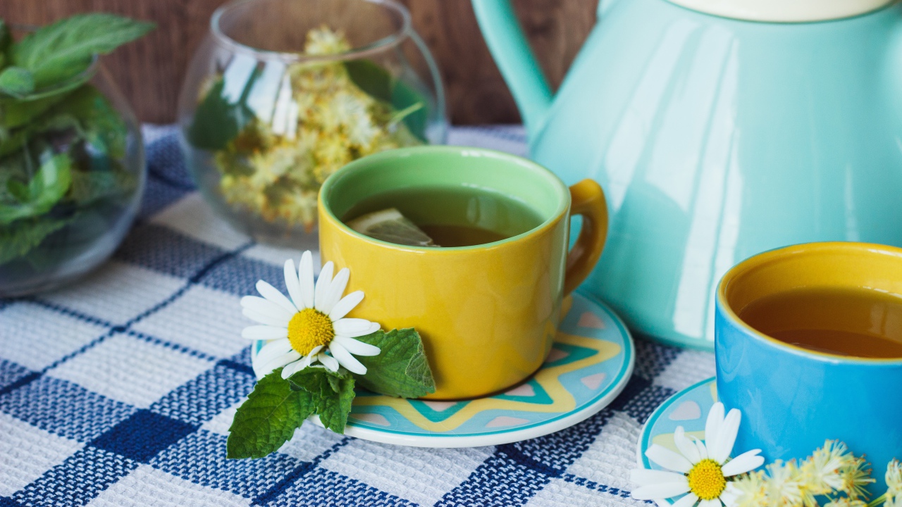 Чай с цветами ромашки в желтой чашке на столе