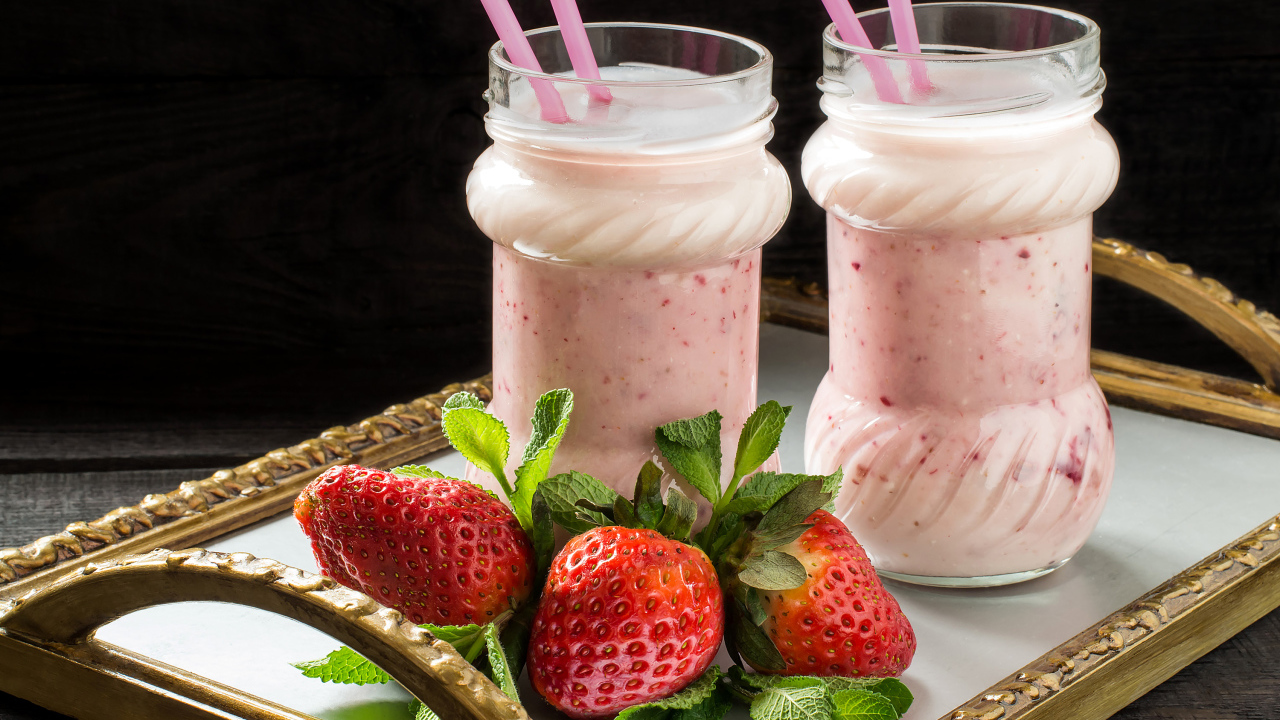 Два свежих клубничных коктейля с трубочками и ягодами клубники