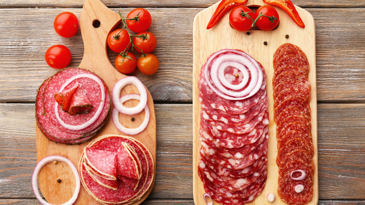 Аппетитная колбасная нарезка на разделочной доске с кольцами лука