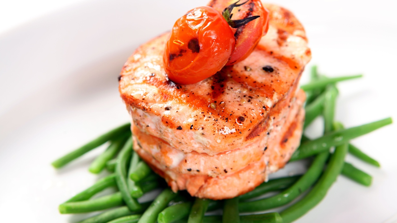 Кусок запеченной рыбы на тарелке с помидорами