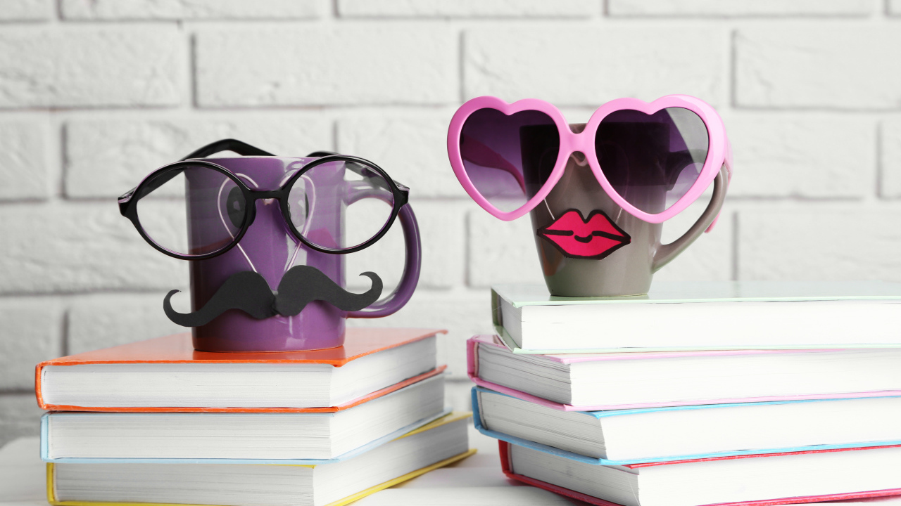 Two funny cups in glasses stand on books