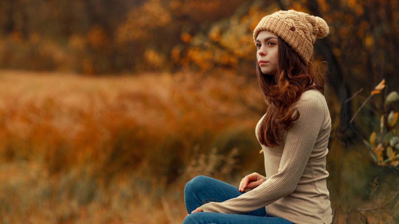 Молодая девушка в синих джинсах и теплой шапке