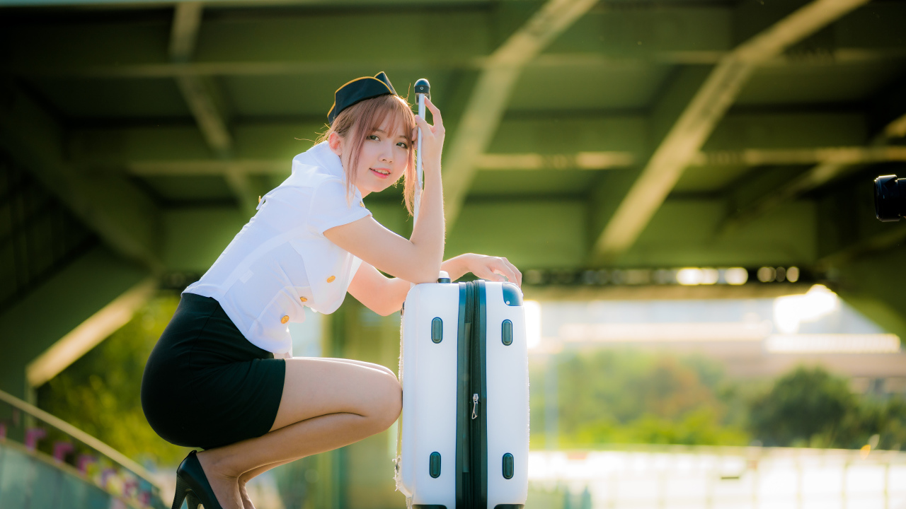 Девушка азиатка стюардесса с чемоданом