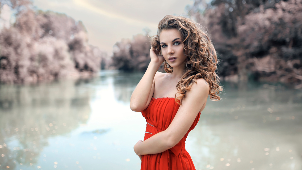 Красивая девушка брюнетка в красном платье у водоема
