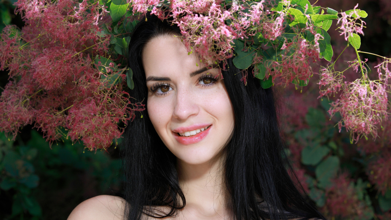 Красивая брюнетка стоит у цветущей ветки