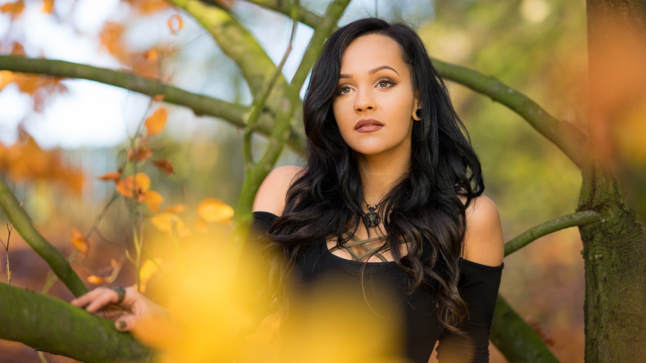 Красивая брюнетка у дерева в черном платье