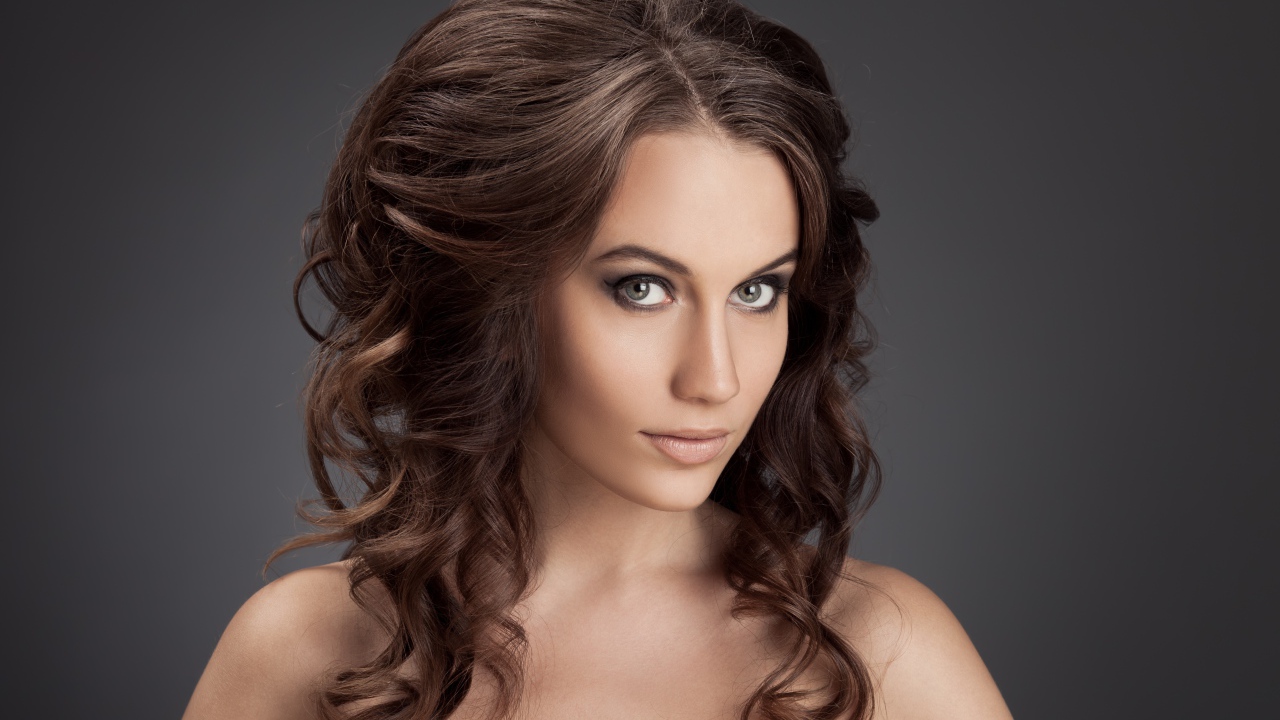 Красивая девушка с волнистыми волосами фото на сером фоне