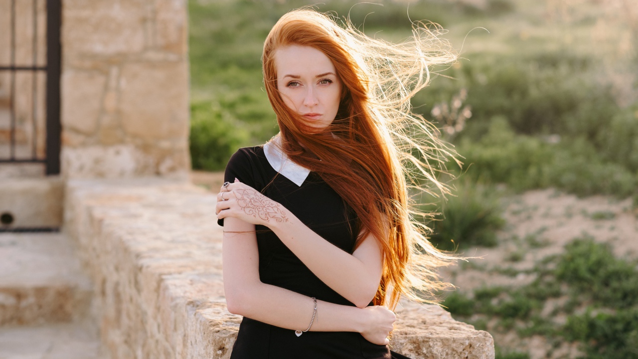 Красивая рыжеволосая девушка в черном платье с рисунком на руке
