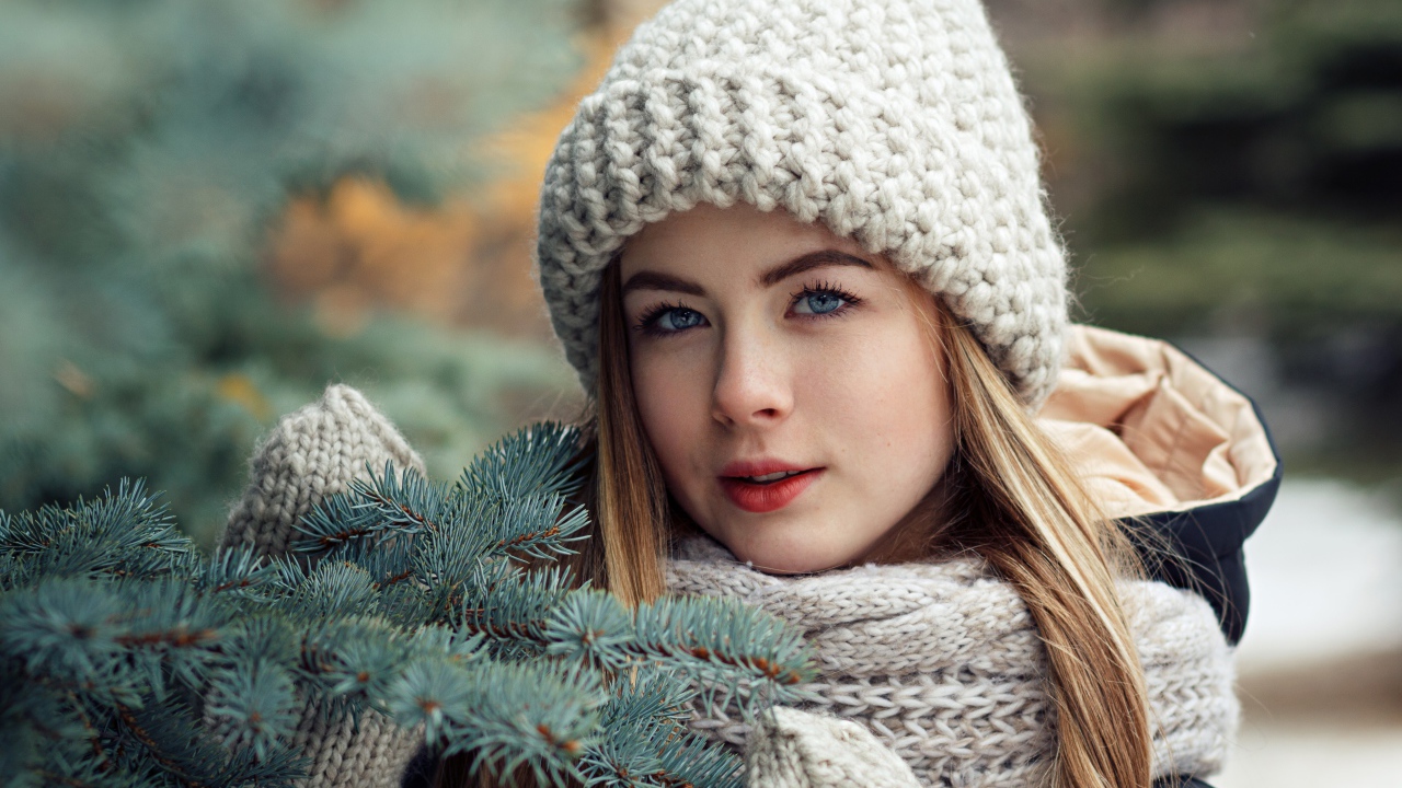 Красивая молодая голубоглазая девушка у еловой ветки зимой