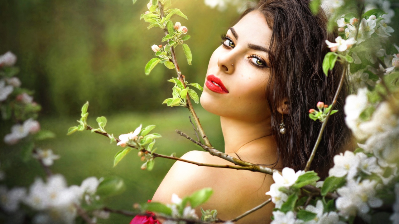 Красивая молодая девушка в ветках цветущей яблони 