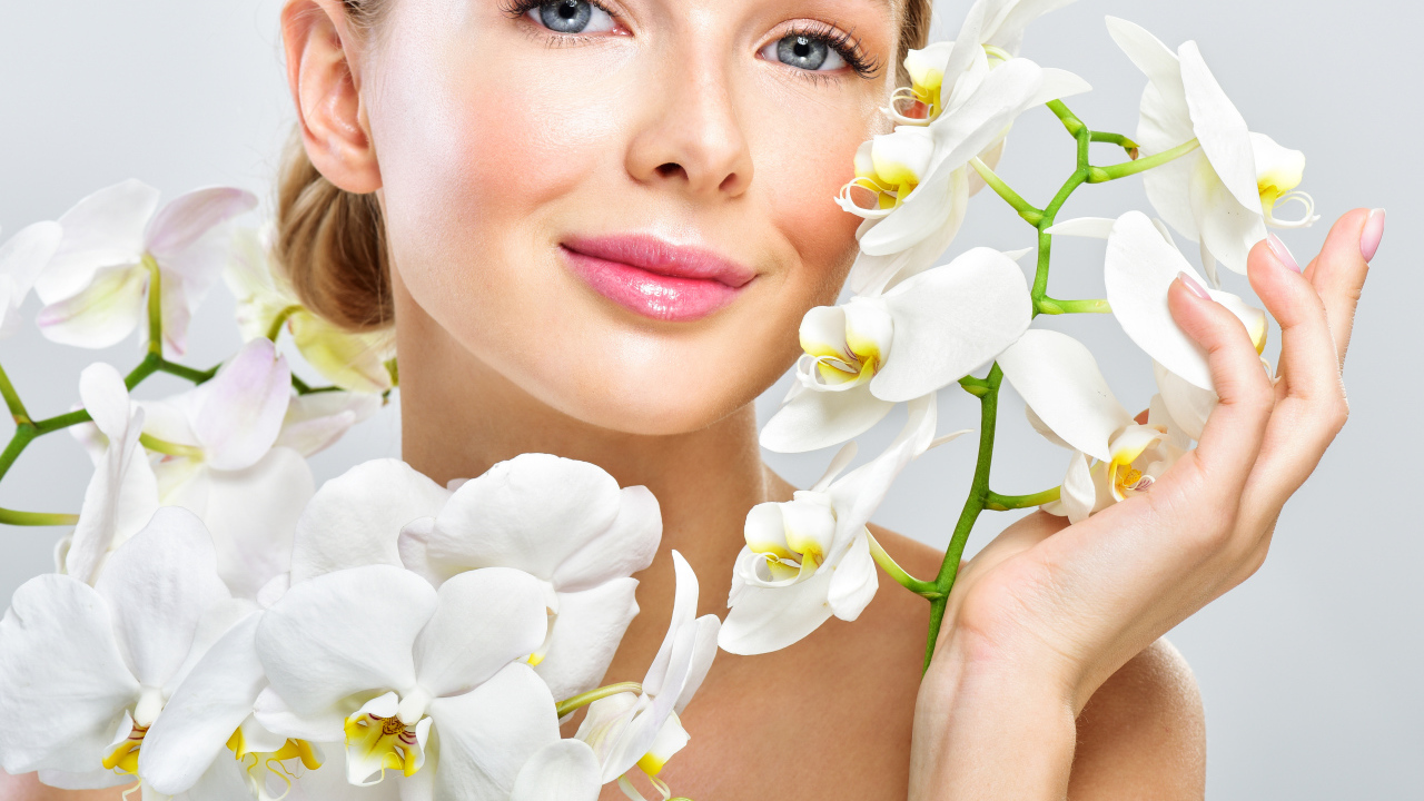 Нежная голубоглазая девушка с цветами орхидеи в руках