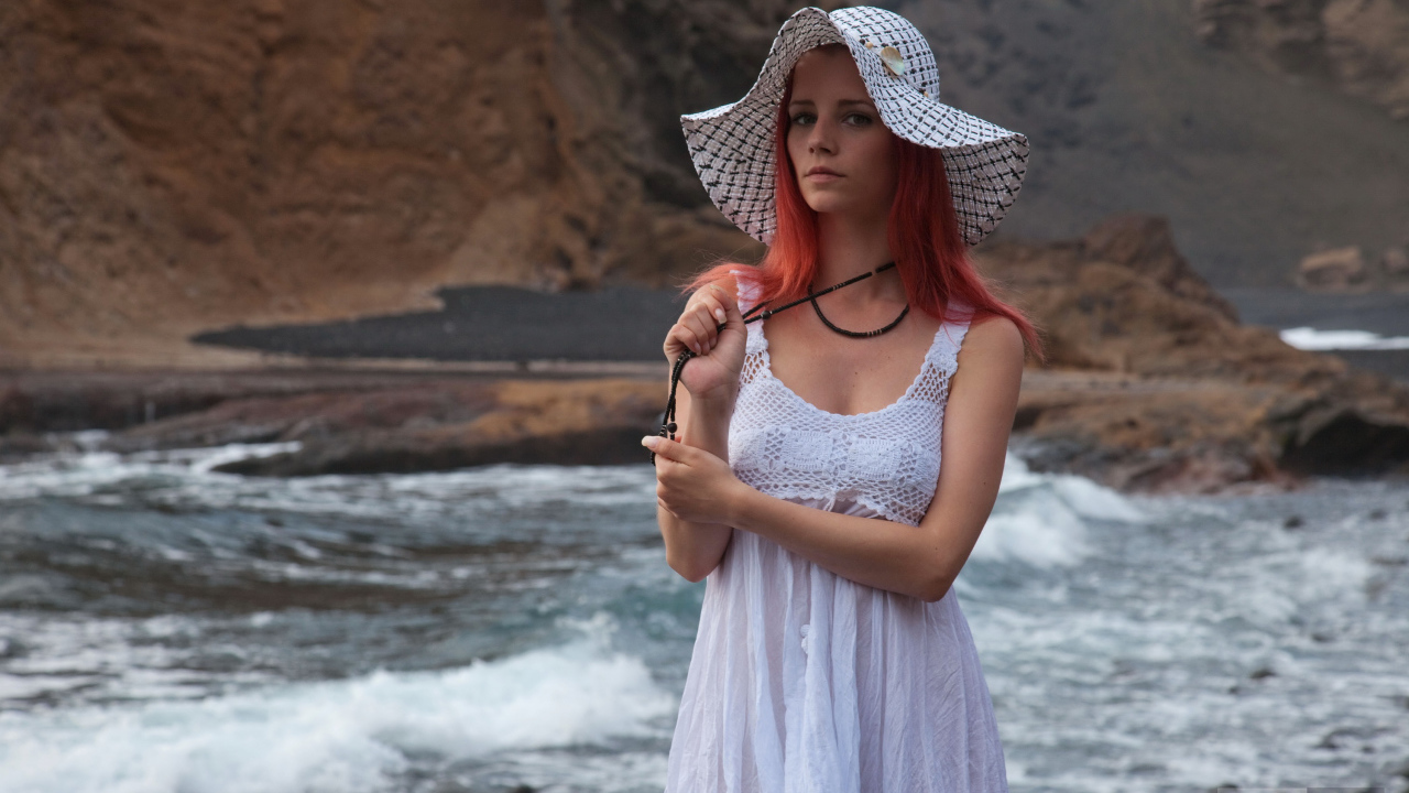 Рыжеволосая девушка в шляпе и белом платье у реки