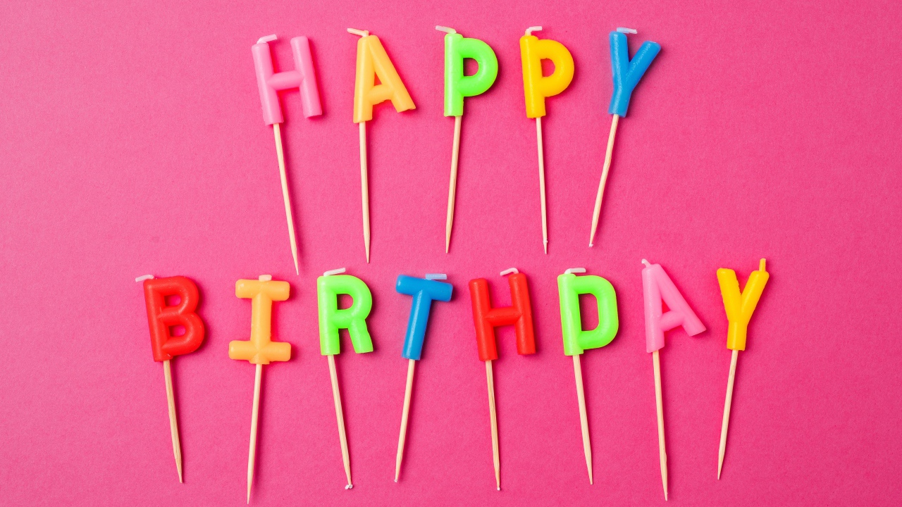 Праздничные свечи с надписью Happy Birthday на розовом фоне